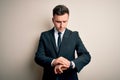 Young handsome business man wearing elegant suit and tie over isolated background Checking the time on wrist watch, relaxed and Royalty Free Stock Photo