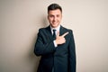 Young handsome business man wearing elegant suit and tie over isolated background cheerful with a smile on face pointing with hand Royalty Free Stock Photo