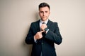 Young handsome business man wearing elegant suit and tie over isolated background In hurry pointing to watch time, impatience, Royalty Free Stock Photo