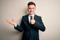 Young handsome business man wearing elegant suit and tie over isolated background Showing palm hand and doing ok gesture with Royalty Free Stock Photo