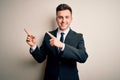 Young handsome business man wearing elegant suit and tie over isolated background smiling and looking at the camera pointing with Royalty Free Stock Photo