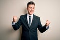 Young handsome business man wearing elegant suit and tie over isolated background very happy and excited doing winner gesture with Royalty Free Stock Photo