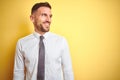 Young handsome business man wearing elegant white shirt over yellow isolated background looking away to side with smile on face, Royalty Free Stock Photo