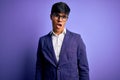 Young handsome business man wearing jacket and glasses over isolated purple background In shock face, looking skeptical and Royalty Free Stock Photo