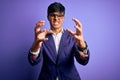 Young handsome business man wearing jacket and glasses over isolated purple background Shouting frustrated with rage, hands trying Royalty Free Stock Photo