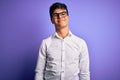 Young handsome business man wearing shirt and glasses over isolated purple background Relaxed with serious expression on face Royalty Free Stock Photo