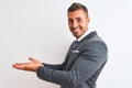 Young handsome business man wearing suit and tie over isolated background pointing aside with hands open palms showing copy space, Royalty Free Stock Photo