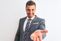 Young handsome business man wearing suit and tie over isolated background smiling cheerful offering palm hand giving assistance Royalty Free Stock Photo