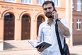 Young handsome business man in white shirt talking on phone outdoors. Self employed Royalty Free Stock Photo