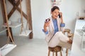 A young handsome business woman is in a good mood while eating a delicious donut and talking on a phone in a pastry shop. Pastry Royalty Free Stock Photo