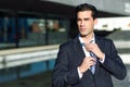 Young handsome businessman adjusting a tie in urban background Royalty Free Stock Photo