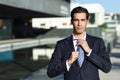 Young handsome businessman adjusting a tie in urban background Royalty Free Stock Photo