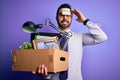 Young handsome businessman with beard holding cardboard box with fired reminder on head stressed with hand on head, shocked with Royalty Free Stock Photo