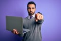 Young handsome businessman with beard working using laptop over purple background pointing with finger to the camera and to you, Royalty Free Stock Photo