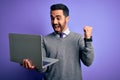 Young handsome businessman with beard working using laptop over purple background screaming proud and celebrating victory and Royalty Free Stock Photo