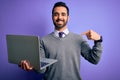 Young handsome businessman with beard working using laptop over purple background with surprise face pointing finger to himself Royalty Free Stock Photo