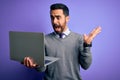 Young handsome businessman with beard working using laptop over purple background very happy and excited, winner expression Royalty Free Stock Photo