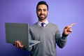 Young handsome businessman with beard working using laptop over purple background very happy pointing with hand and finger to the Royalty Free Stock Photo