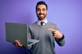 Young handsome businessman with beard working using laptop over purple background very happy pointing with hand and finger Royalty Free Stock Photo