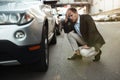 Young handsome businessman checking wheel of his car having problems on the road , unexpectable vehicle trouble