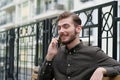 Young handsome businessman sits on the bench and speaks on smartphone Royalty Free Stock Photo