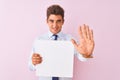 Young handsome businessman holding banner standing over isolated pink background with open hand doing stop sign with serious and Royalty Free Stock Photo