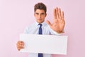 Young handsome businessman holding banner standing over isolated pink background with open hand doing stop sign with serious and Royalty Free Stock Photo