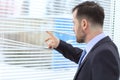 Young and handsome businessman looking out of the window through the blinds Royalty Free Stock Photo