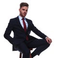 Young handsome businessman in navy suit resting on wooden chair Royalty Free Stock Photo