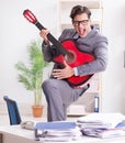 Young handsome businessman playing guitar in the office Royalty Free Stock Photo