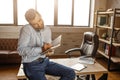 Young handsome businessman sit on table and talk on phone in his own office. He write in notebook. Business call