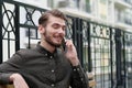 Young handsome businessman sits on the bench and speaks on smartphone Royalty Free Stock Photo