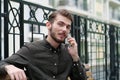 Young handsome businessman sits on bench and talks on mobile phone Royalty Free Stock Photo