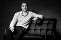 Young handsome businessman sitting with confidence on leather couch thinking Royalty Free Stock Photo
