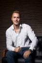 Young handsome businessman sitting with confidence on leather couch thinking Royalty Free Stock Photo