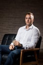 Young handsome businessman sitting on leather couch with phone in hand and thinking Royalty Free Stock Photo