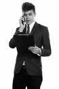 Young handsome businessman talking on mobile phone while reading on clipboard Royalty Free Stock Photo