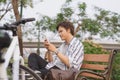 Young handsome businessman talking by mobile phone while sitting on bench in park after riding bicycle Royalty Free Stock Photo