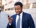 Young handsome businessman using mobile phone app sending message outside office in urban city Royalty Free Stock Photo