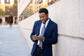 Young handsome businessman using mobile phone app sending message outside office in urban city Royalty Free Stock Photo