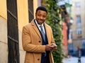 Young handsome businessman using mobile phone app sending message outside office in urban city Royalty Free Stock Photo