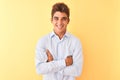 Young handsome businessman wearing elegant shirt over isolated yellow background happy face smiling with crossed arms looking at Royalty Free Stock Photo