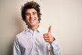 Young handsome businessman wearing elegant shirt standing over isolated white background doing happy thumbs up gesture with hand Royalty Free Stock Photo