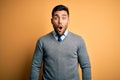 Young handsome businessman wearing elegant sweater and tie over yellow background afraid and shocked with surprise expression, Royalty Free Stock Photo