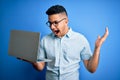 Young handsome businessman wearing glasses working using laptop over blue background very happy and excited, winner expression Royalty Free Stock Photo