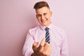 Young handsome businessman wearing shirt and tie standing over isolated pink background Beckoning come here gesture with hand