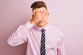 Young handsome businessman wearing shirt and tie standing over isolated pink background covering eyes with hand, looking serious Royalty Free Stock Photo