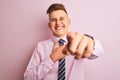 Young handsome businessman wearing shirt and tie standing over isolated pink background laughing at you, pointing finger to the Royalty Free Stock Photo