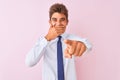 Young handsome businessman wearing shirt and tie standing over isolated pink background laughing at you, pointing finger to the Royalty Free Stock Photo