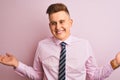 Young handsome businessman wearing shirt and tie standing over isolated pink background smiling showing both hands open palms, Royalty Free Stock Photo